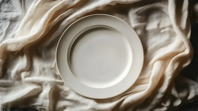 Top view of a minimalist white plate centered on beige wrinkled cloth