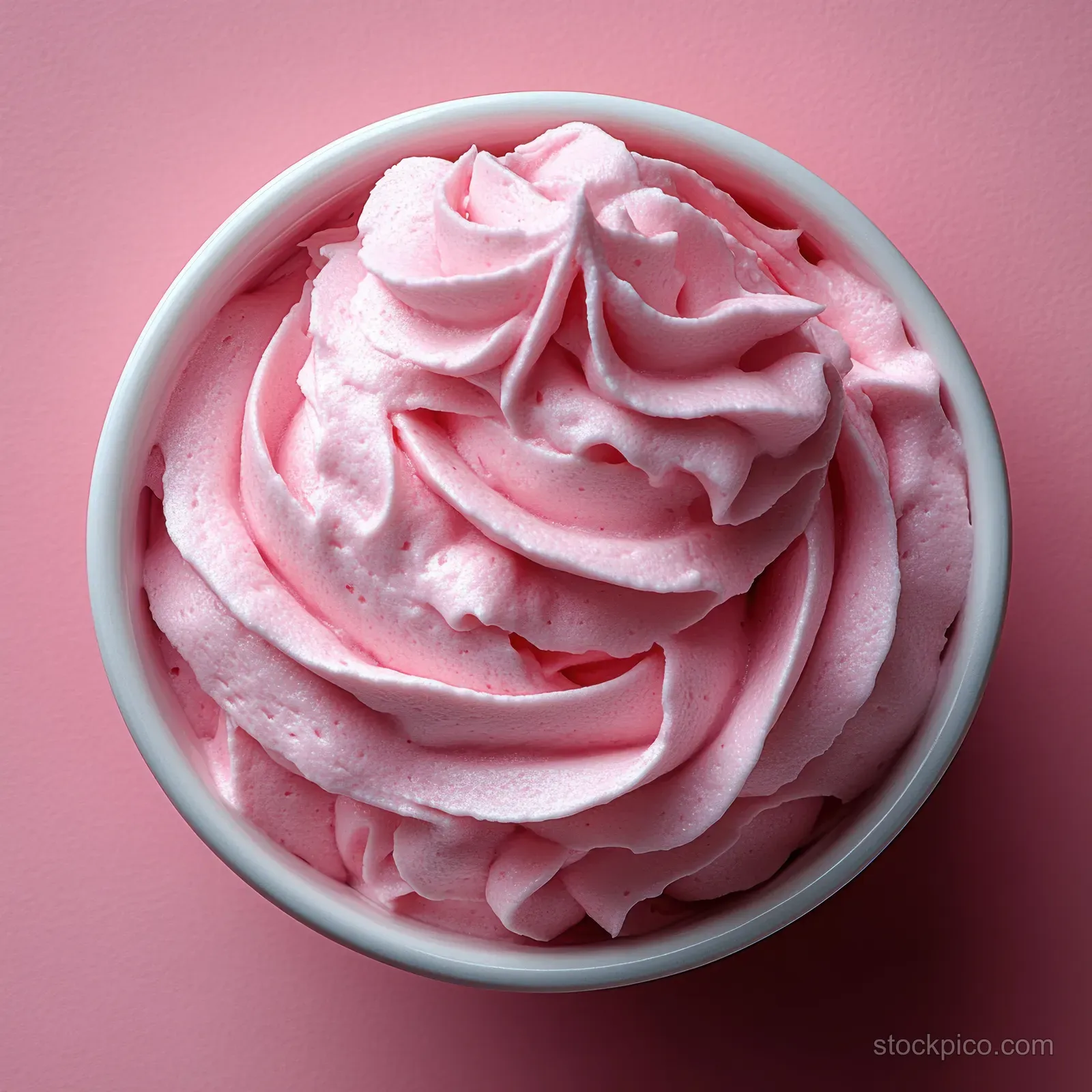 Pink sugar scrub cream swirled in a bowl with visible granules on a pastel background.