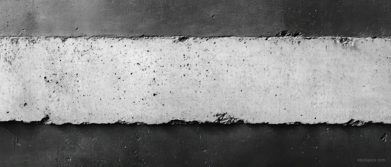 Close-up of a worn concrete wall with rough chipped edges and horizontal black stripes on a grayed surface.