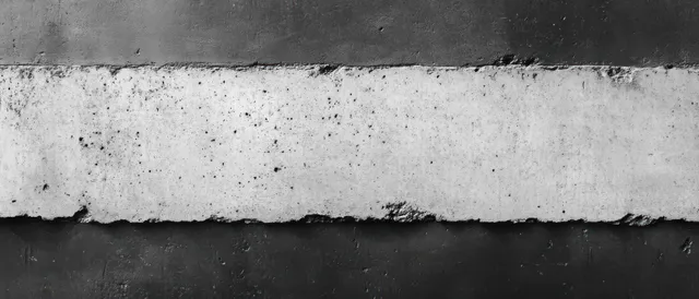 Close-up of a worn concrete wall with rough chipped edges and horizontal black stripes on a grayed surface.