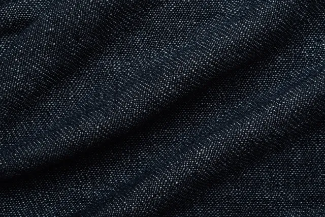 Close-up of black denim fabric texture with visible woven threads and folded surface.
