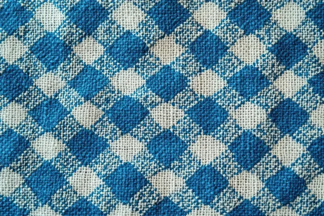 Close-up of blue and beige diamond plaid woven fabric showing textured thread and repeating square pattern.