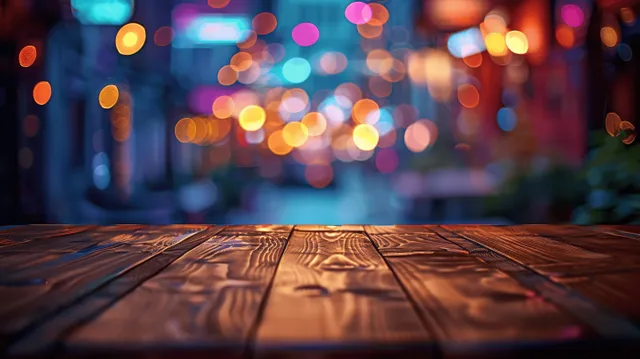 Empty wooden table in the foreground with neon streetlight bokeh and a dark bar-like interior background.