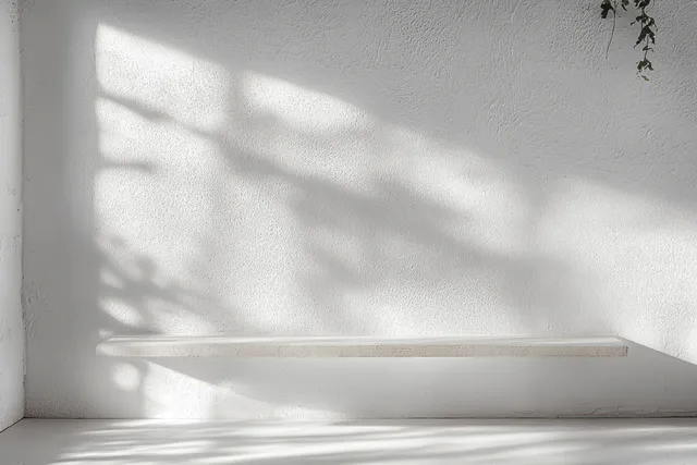 Minimal white textured wall studio with floating shelf, soft sunlight and gentle shadow lines