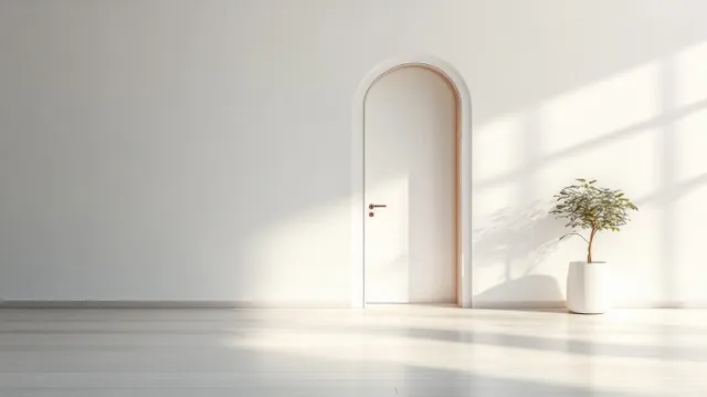 A half-open white door lets bright light spill into a minimal interior with a small potted plant.