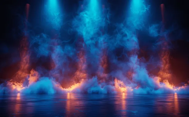 Empty concert stage at night with blue spotlights cutting through drifting smoke and glowing floor haze.