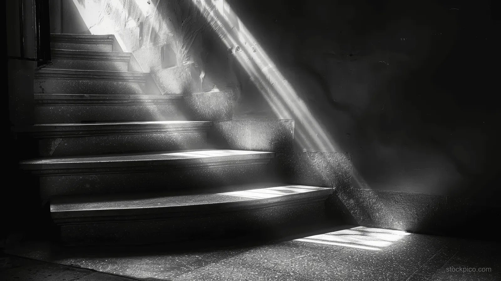 A dark staircase in an old house illuminated by sunlight rays, casting long high-contrast shadows on the steps.
