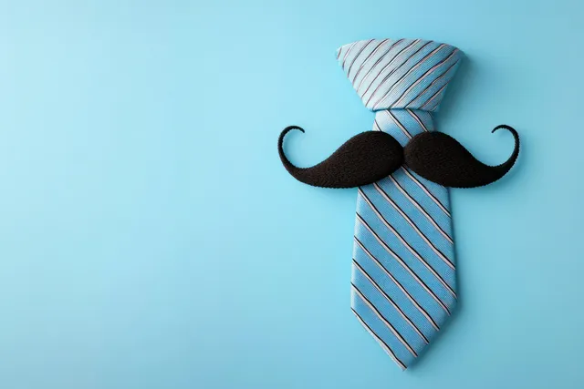 Blue striped necktie with a curled black mustache attached, arranged as a whimsical face on light blue.