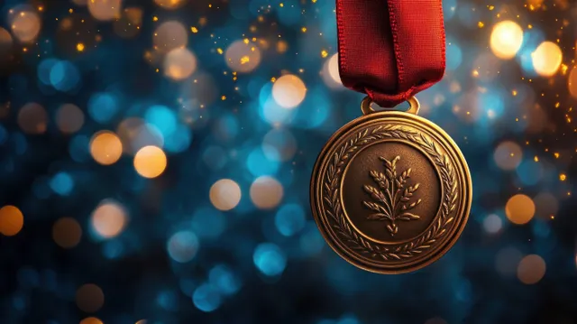 Gold laurel medal on a red ribbon hanging above blue and orange bokeh lights.