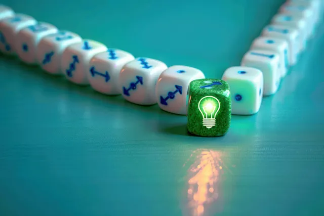 A glowing green die marked with a light bulb icon sits ahead of white dice with blue arrows on a teal surface.