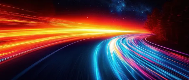 Neon blue and orange light trails curve along a night racetrack under heavy motion blur.
