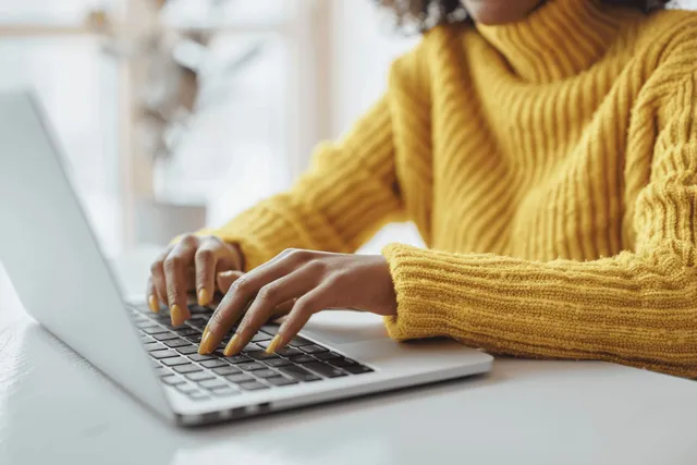 Close-Up of a Woman Typing on a Laptop in a Modern Office