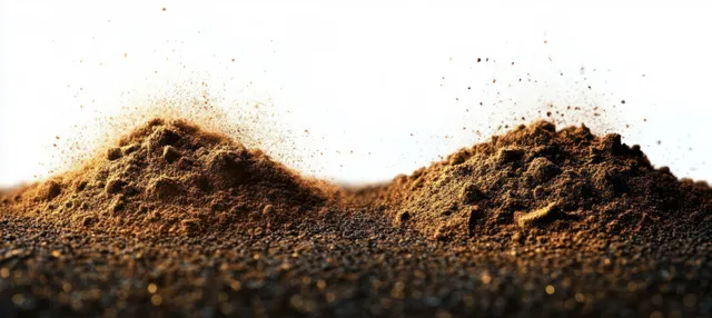 Two piles of finely ground coffee on a white background with powder particles floating around them.