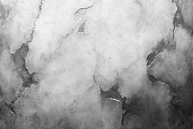 Close-up view of a cracked gray concrete wall with peeling plaster and rough uneven weathered texture.