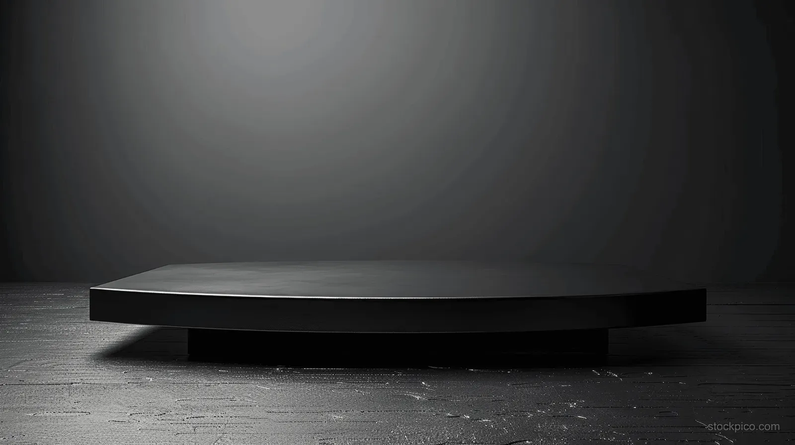An empty black table sits on a dark grey studio floor under a soft spotlight, leaving space on the background.