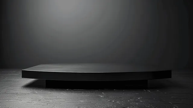 An empty black table sits on a dark grey studio floor under a soft spotlight, leaving space on the background.