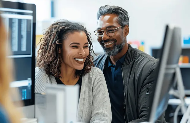 Diverse coworkers reviewing data on office monitor during collaborative project meeting