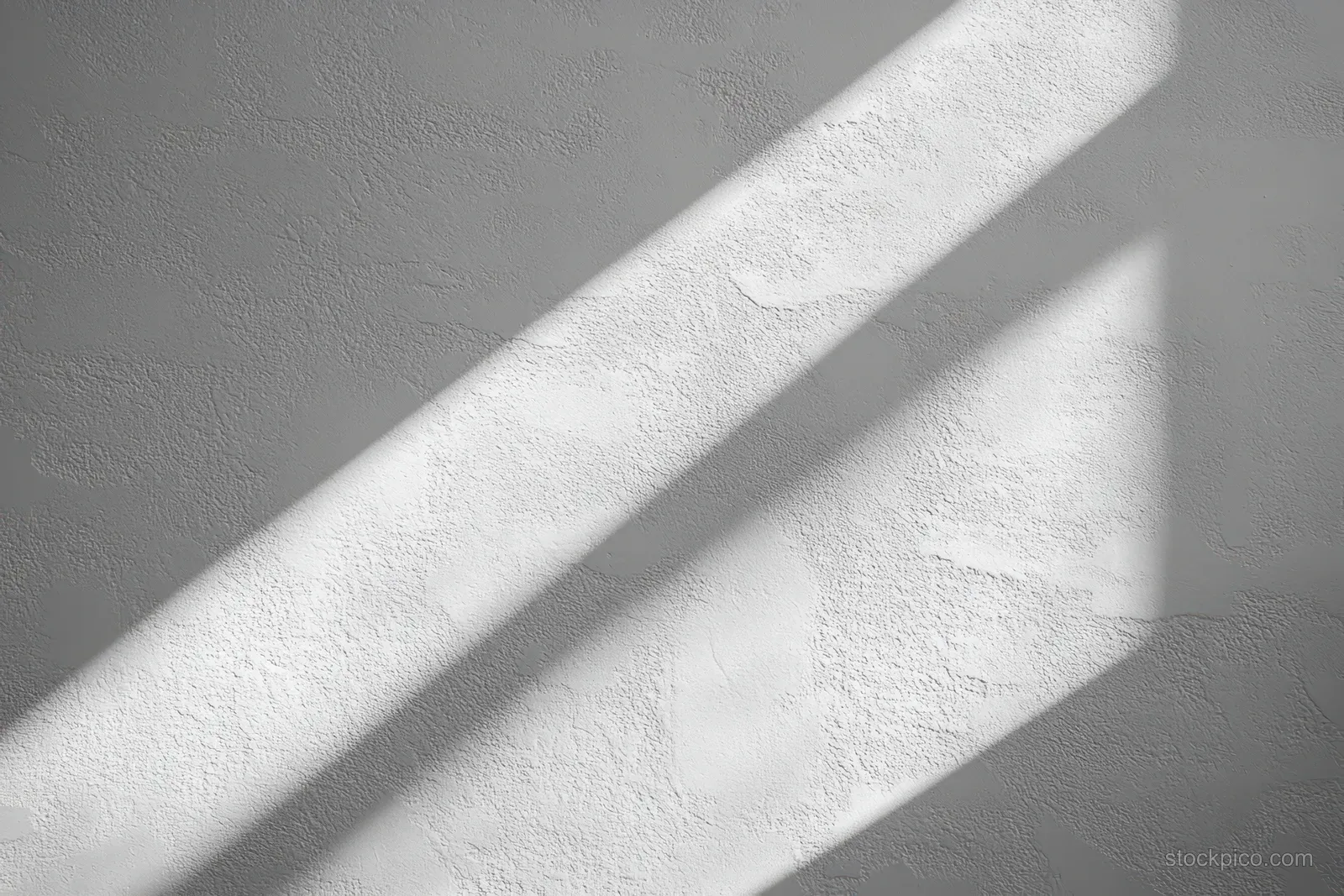 Diagonal sunlight creates crisp shadow stripes on a textured white wall indoors.