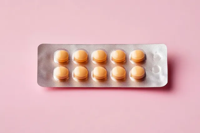 Ten round yellow tablets in an open blister pack displayed on a soft pink background.