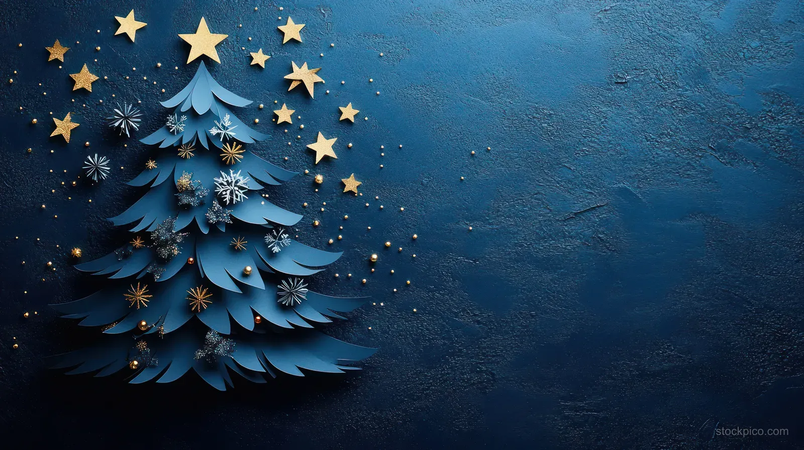Folded paper Christmas tree decorated with gold stars and silver snowflake cutouts on a dark blue textured background.
