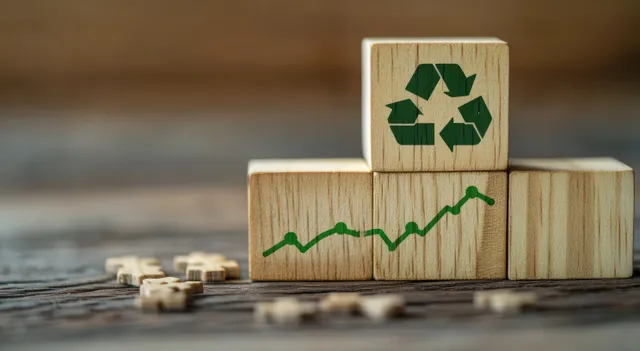 Wooden blocks with recycling symbol and upward green emissions graph on a table