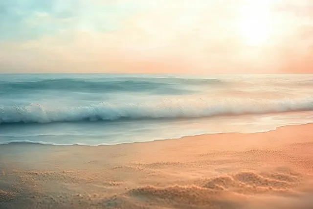 Gentle waves roll onto a sandy beach as warm sunrise light glows over the horizon and soft foam gathers.