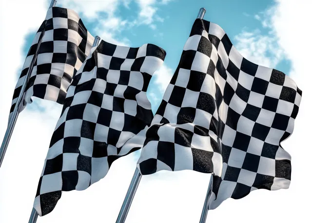 Three black and white checkered flags wave on poles against a partly cloudy blue sky.