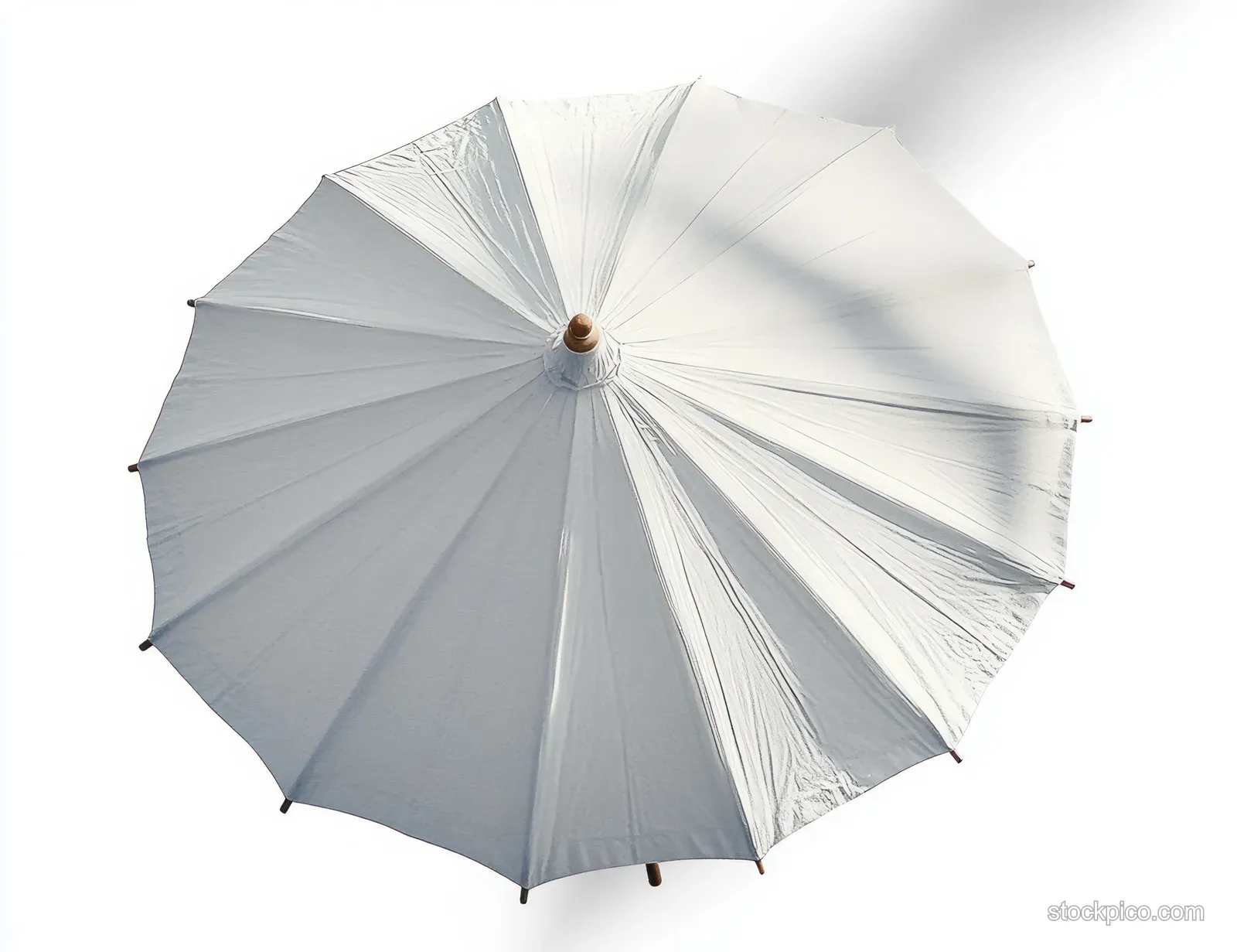 Top view of an open white outdoor umbrella showing fabric ribs and strong shadows on a bright background.
