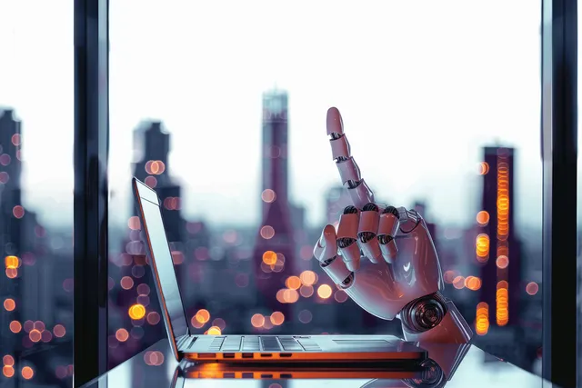 A robotic hand types on a laptop inside a glass office with blurred city lights outside at dusk.
