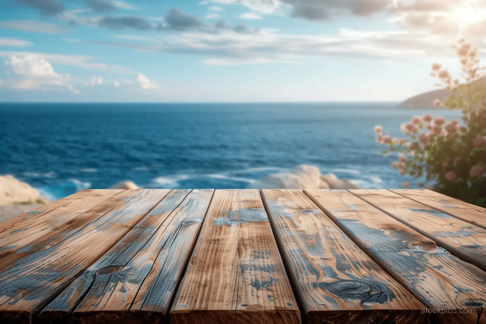 Wooden tabletop foreground with blurred ocean and sunlit sky background.