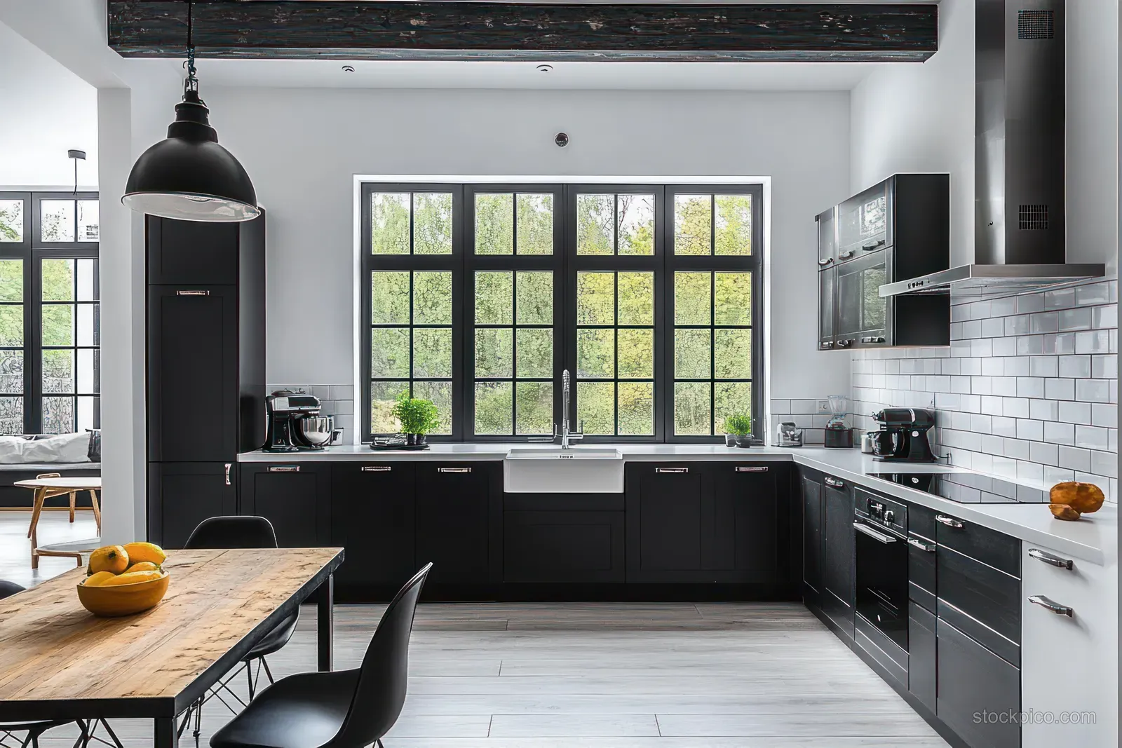 Black cabinet kitchen with white subway tile backsplash, sink, stovetop, and large window letting in natural light.