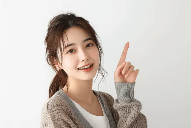 Smiling Japanese businesswoman pointing upward in a clean studio portrait against white background with Head And Shoulders