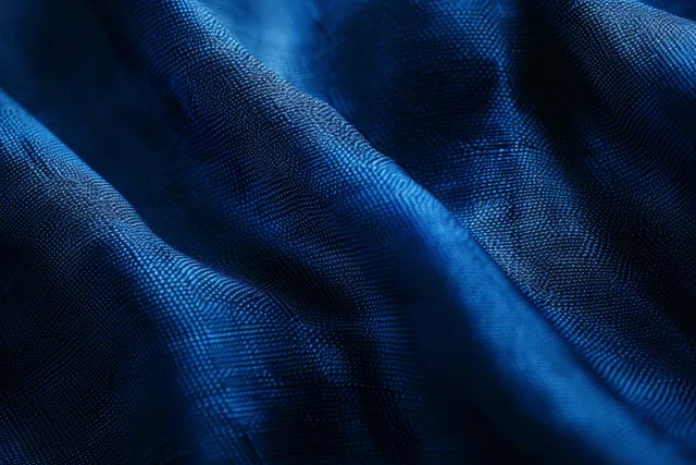 Primer plano de tela de satén azul marino oscuro con pliegues ondulados suaves, un brillo sutil y espacio libre para texto.