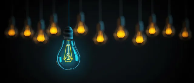 A glowing blue light bulb hangs among several warm yellow bulbs against a dark background.