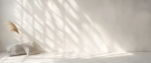 Tropical leaf shadows stretch across a white wall, minimal abstract texture