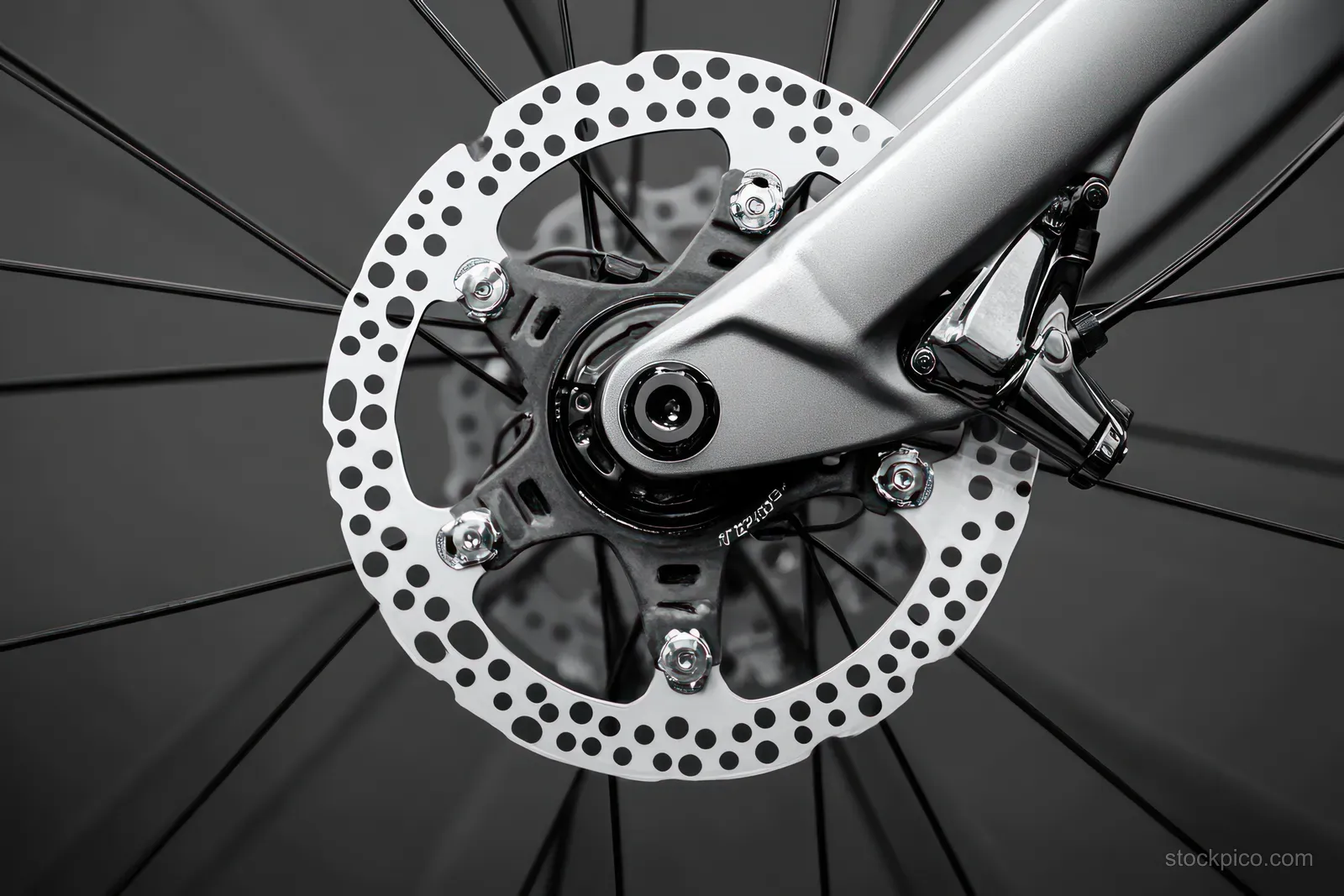 Disc brake rotor and wheel hub with thin spokes in sharp focus on a dark blurred background.