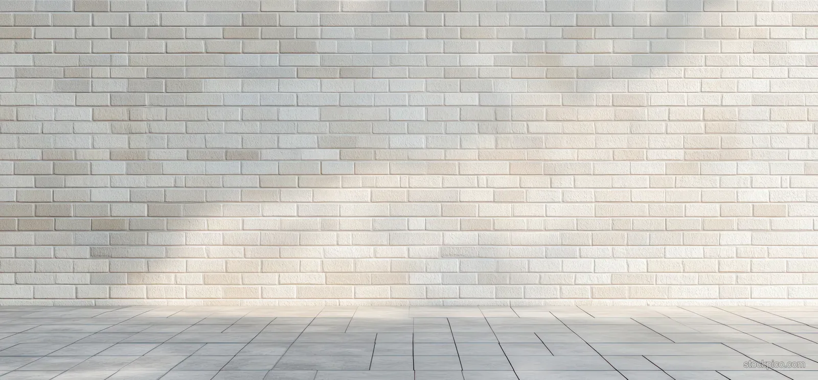 Empty corner room with a white brick wall and gray tiled floor illuminated by soft natural light.