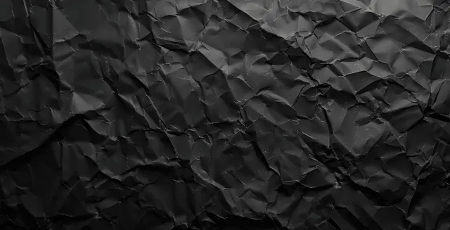 Crumpled black paper texture with deep wrinkles and grunge shadows filling the background.