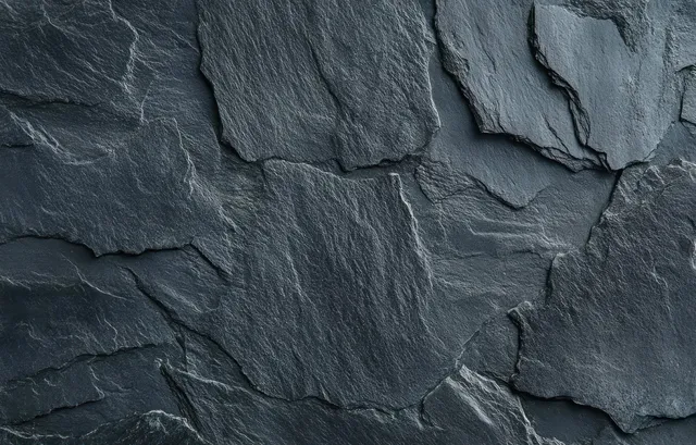 Overlapping dark gray slate stones in a rough wall surface with visible cracks and layered seams.