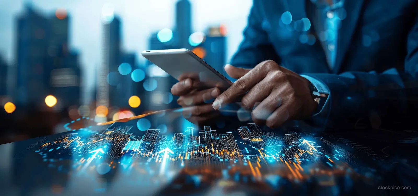 A businessman holds a tablet and reviews glowing stock charts with a laptop beside him in a city at night.