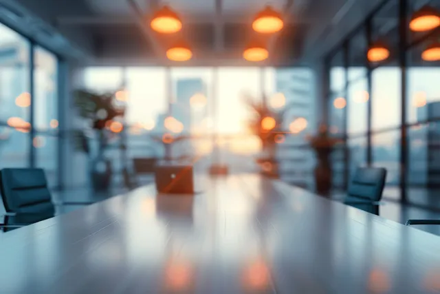 Defocused conference room interior shows a long table, chair outlines, and window light glow in a depthy perspective.