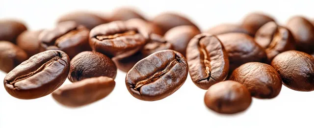 Glossy roasted coffee beans scattered on a white background with visible macro surface texture.