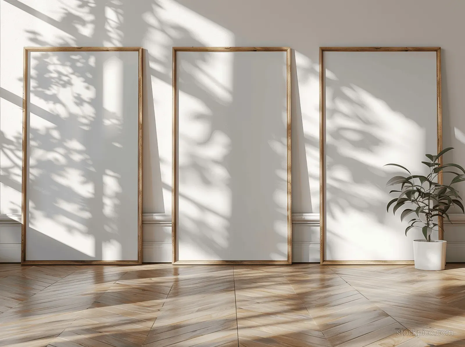 Three empty wooden picture frames on a sunlit parquet floor with sharp window shadows in a bright room.