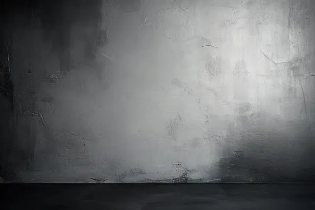 Empty textured concrete wall with worn plaster in grayscale lighting and a dark floor.