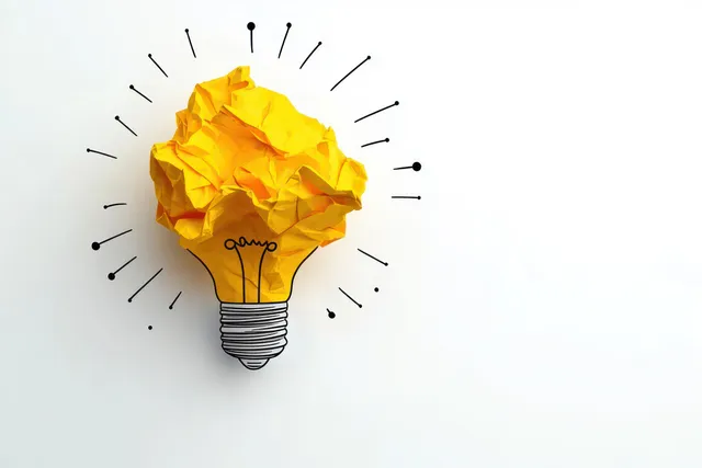 Yellow crumpled paper ball with glowing light bulb symbol on white concept background