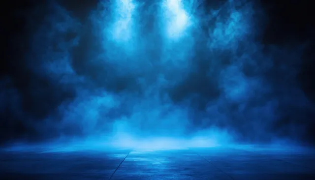 Empty theater stage with blue spotlight beams cutting through heavy smoke