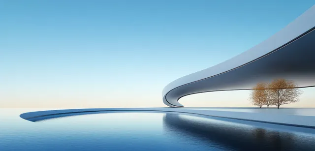 A futuristic curved building edge mirrors in still water beneath a clear blue sky.