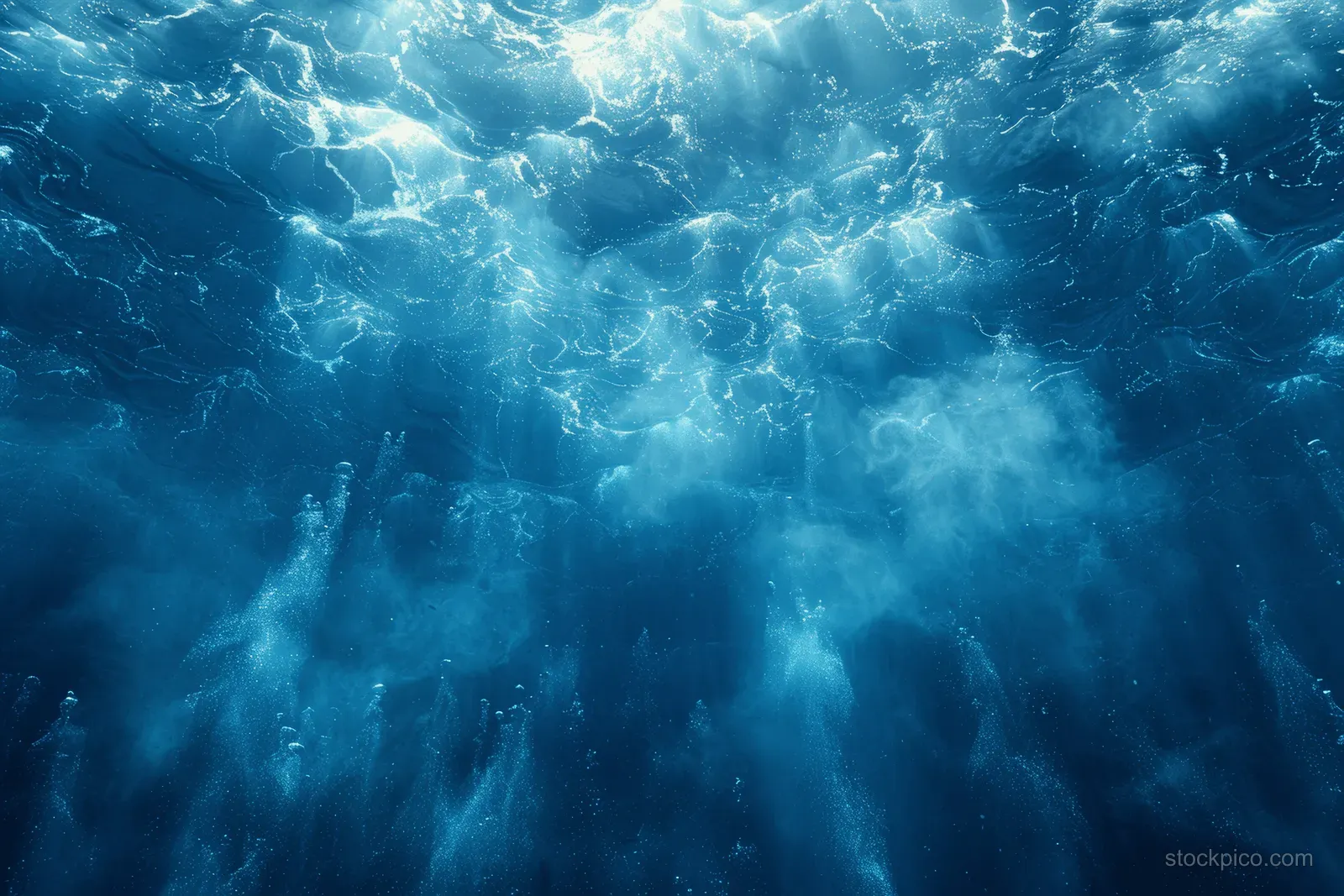 Blue water ripples with bright light rays filtering through the surface.