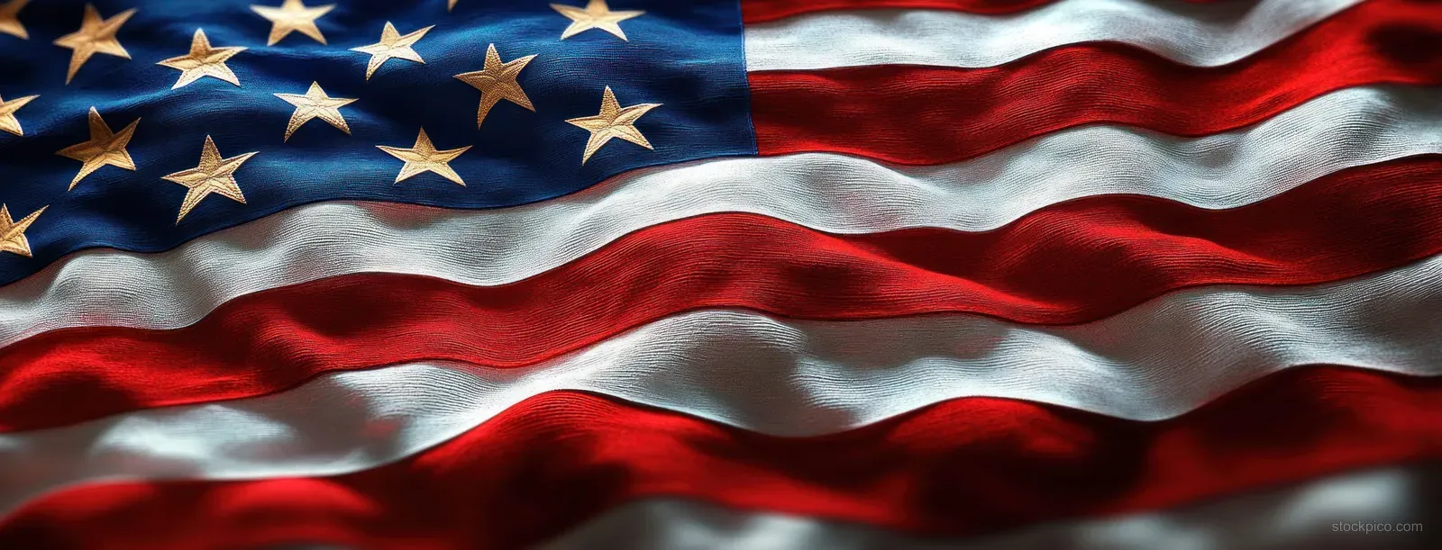 A close-up waving fabric flag with red and white stripes, golden stars, and visible fold texture against blue.