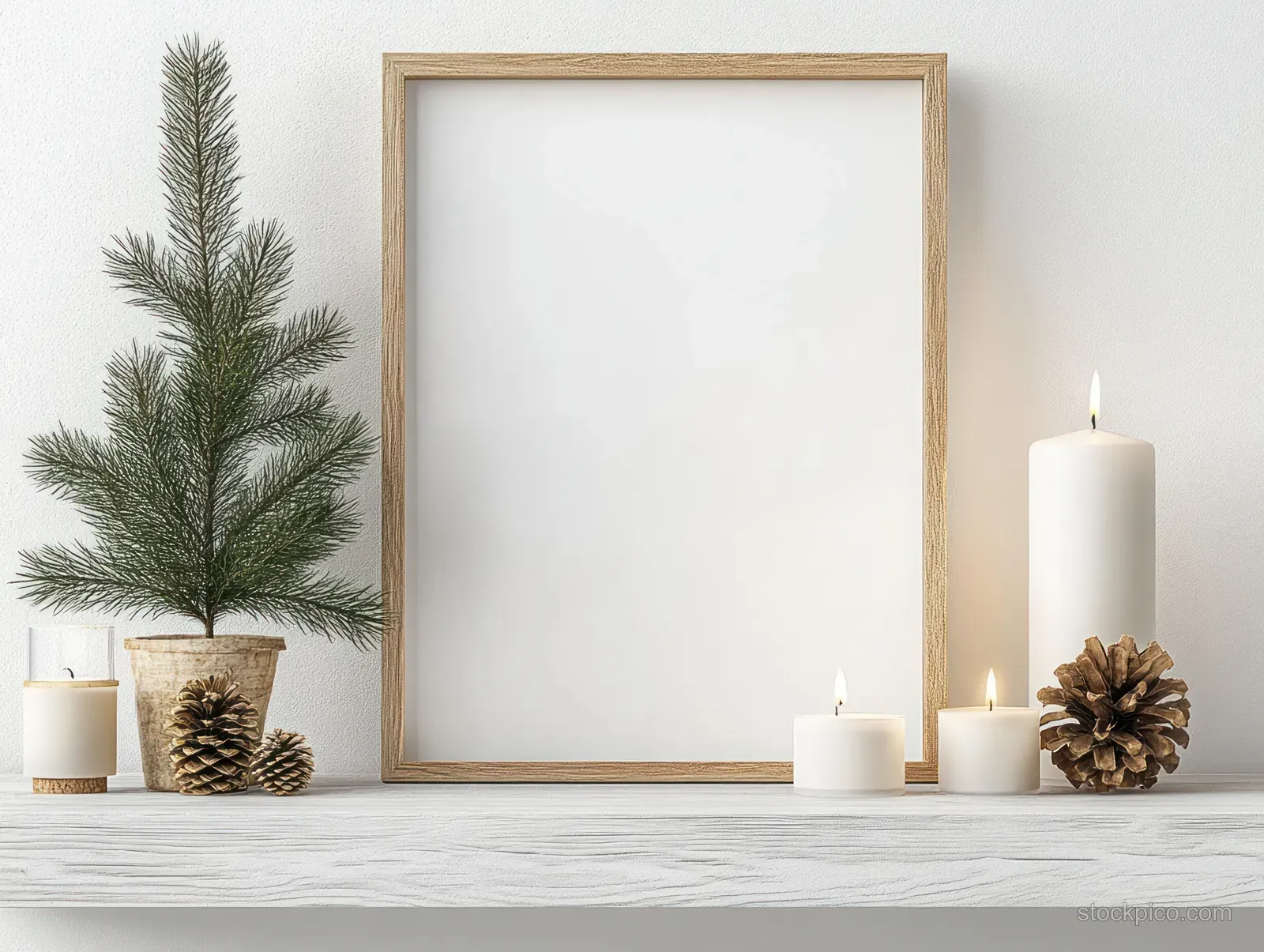Blank wooden frame centered on a white shelf with pine branches, pinecones, and three glowing candles.